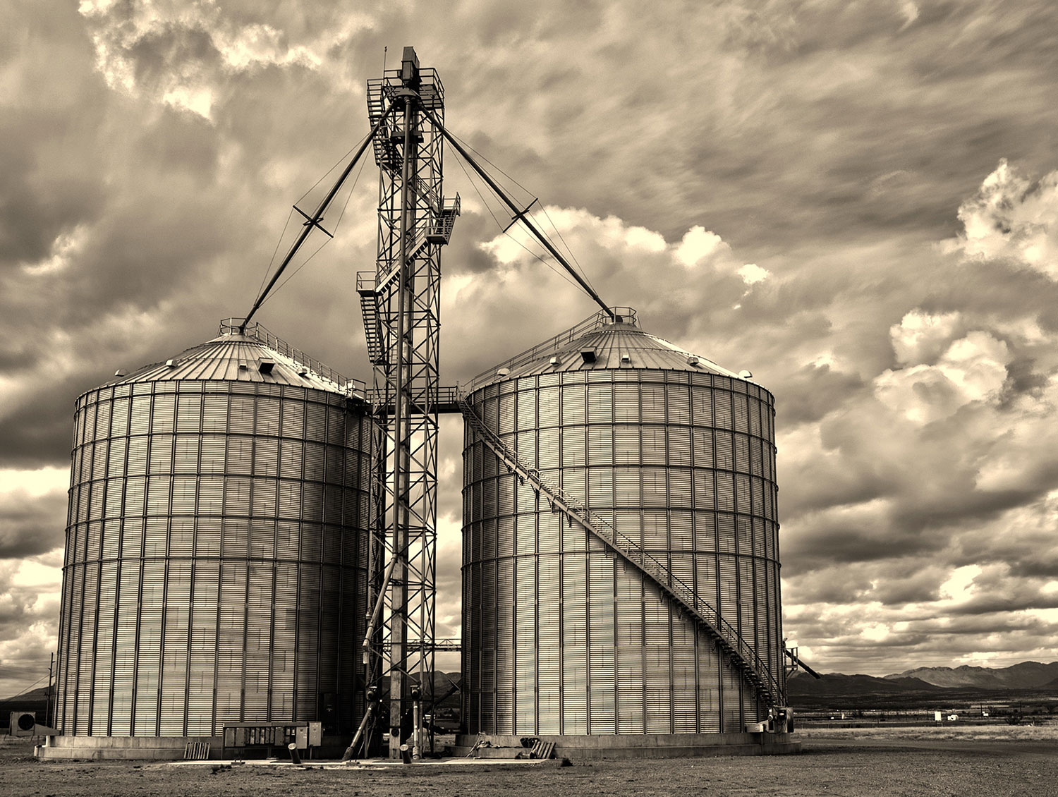 Sepia Saturday: Two silos near Willcox, in Southeastern Arizona, stand guard as clouds threaten rain. Photograph by Kirk Higgins.