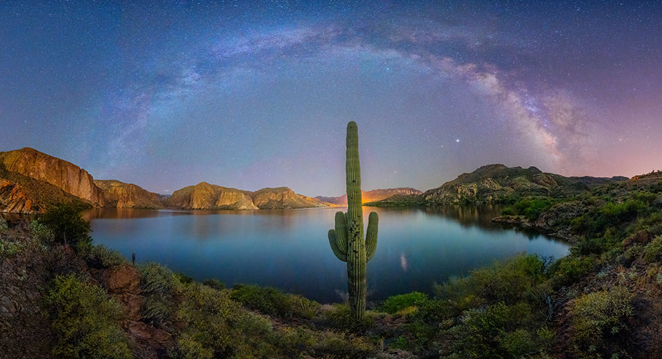 A lone saguaro guards the shore of Canyon Lake, northeast of the Phoenix area, as the Milky Way arches overhead. The glow behind the saguaro is from the lake’s developed area, which includes boat launches, a marina and a steamboat that offers sightseeing cruises. By Sean Parker