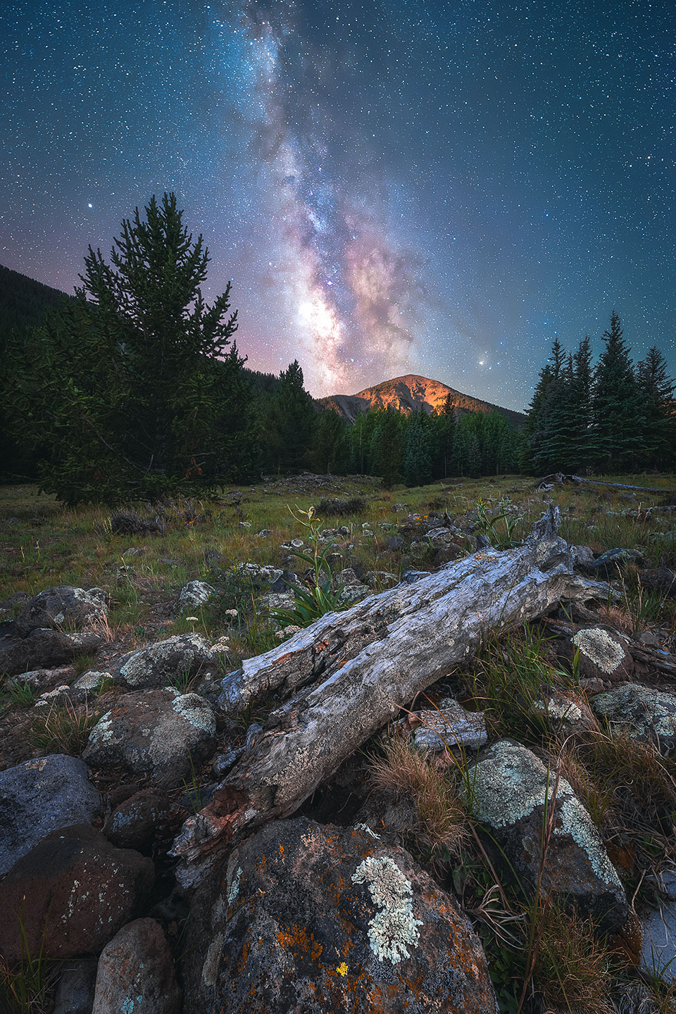 The Milky Way shines brightly in the sky above the Inner Basin of the San Francisco Peaks, near Flagstaff. In the distance, Fremont Peak reflects the light of the rising moon. By Mike Sanchez