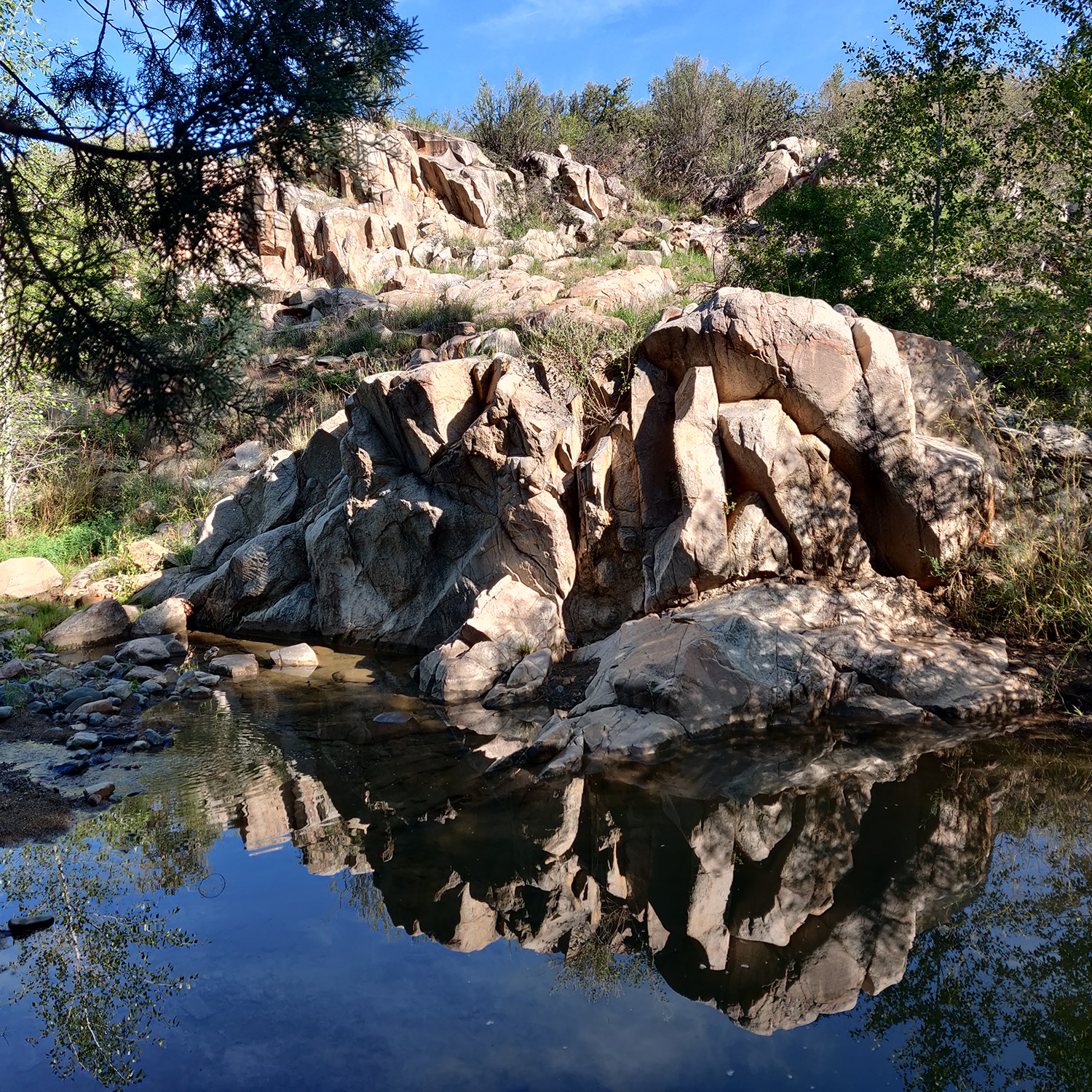 A Lynx Creek reflecting pool mirrors a large granite outcrop near Fain Lake in Prescott Valley. By Kirk Higgins