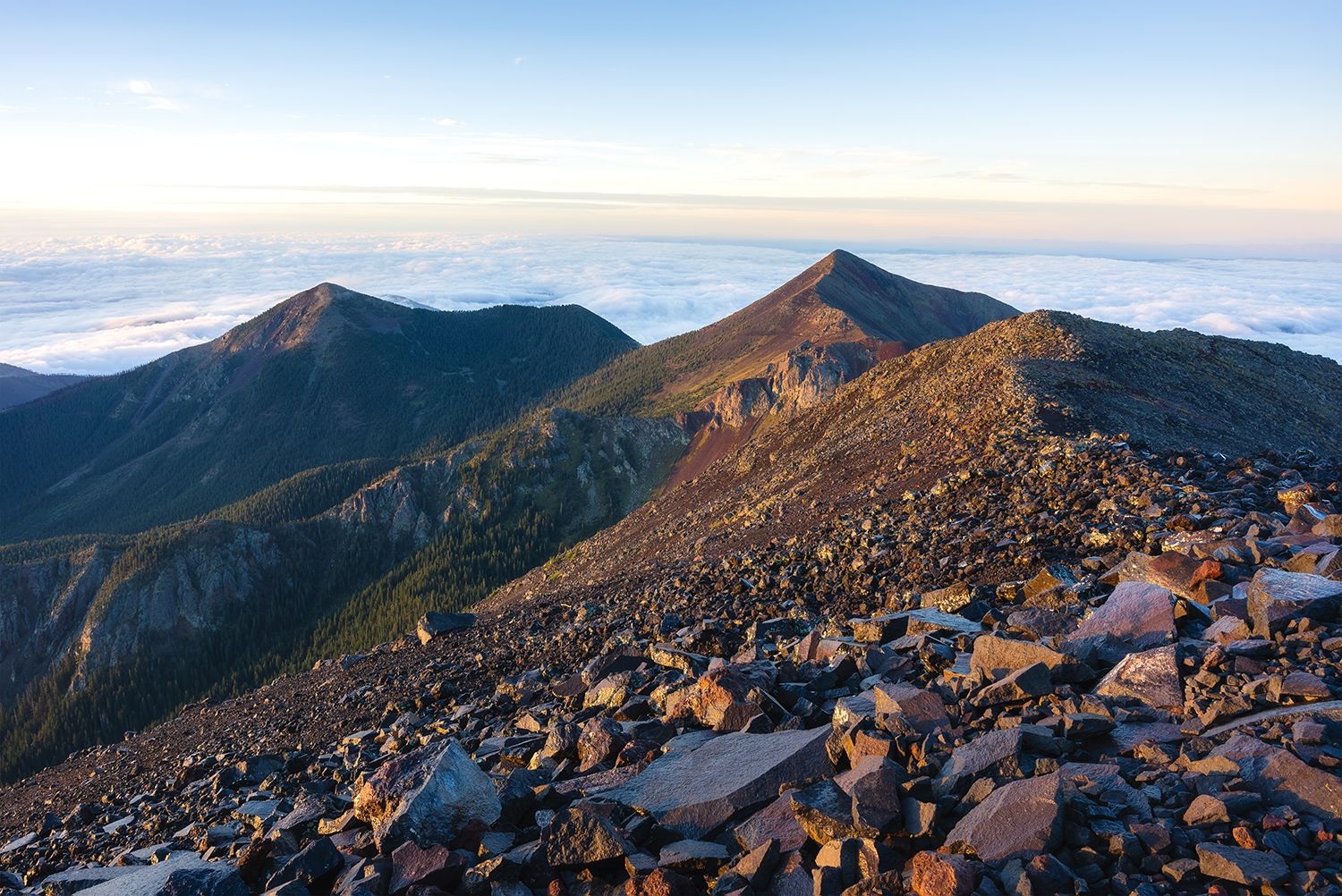 A layer of clouds surrounds the San Francisco Peaks in a view from the summit of Humphreys Peak. By Cameron Kirk