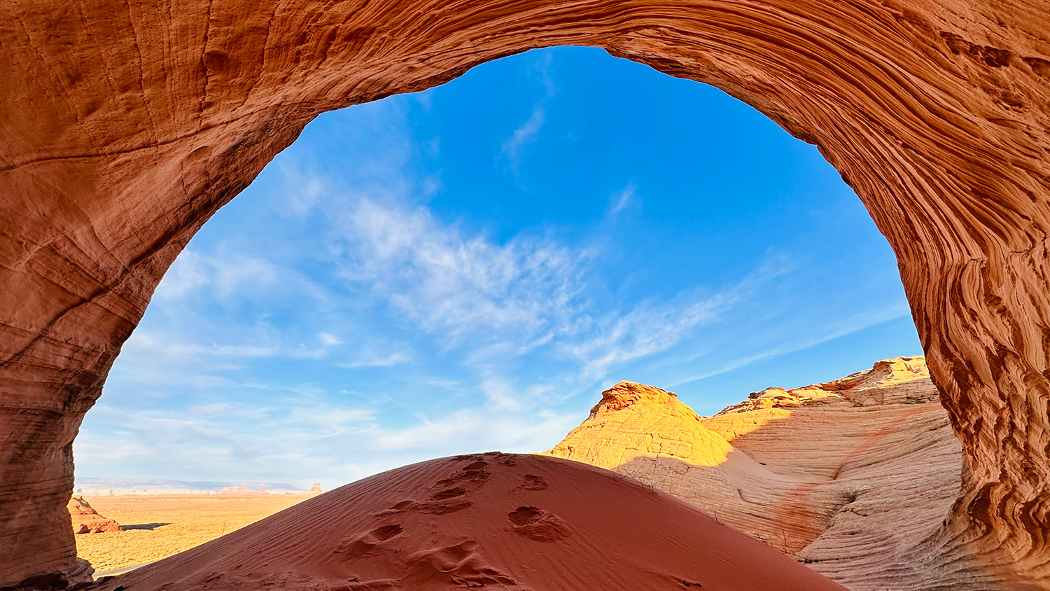 A sandstone arch off State Route 98 frames a view of the high desert of the Navajo Nation. By Mario Begay