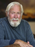 Portrait of David Muench leaning on a leather chair arm. | PAUL MARKOW  ABOVE JOEL GRIMES