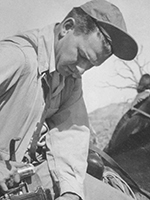 BW photo of Ray Manley lifting a 4x5 camera out of a bag while mounted on a mule in the desert. | COURTESY OF CAROLYN MANLEY ROBINSON