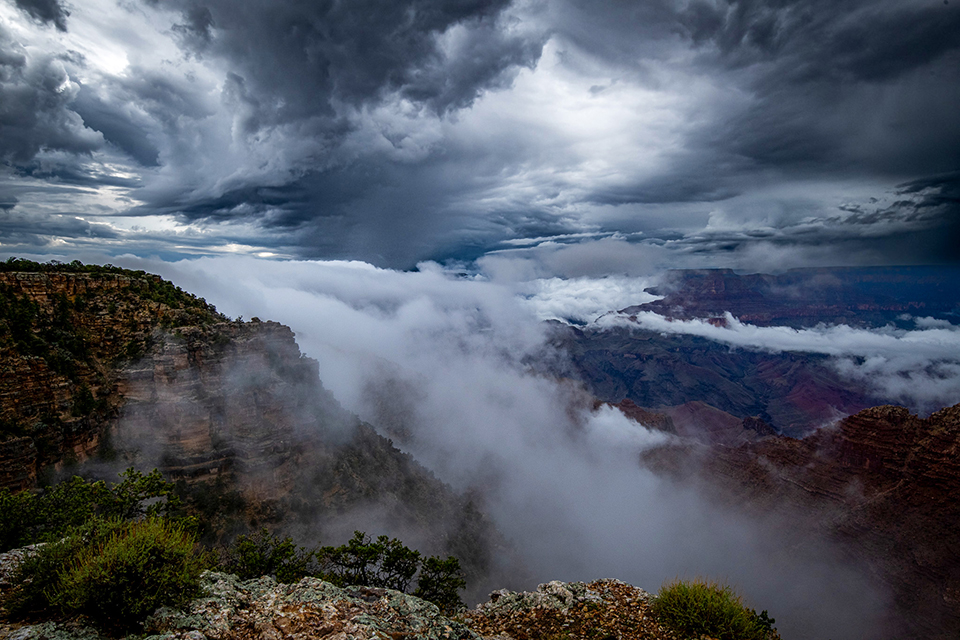 Storm clouds above and below the Grand Canyon's rim begin to clear. By John Fink