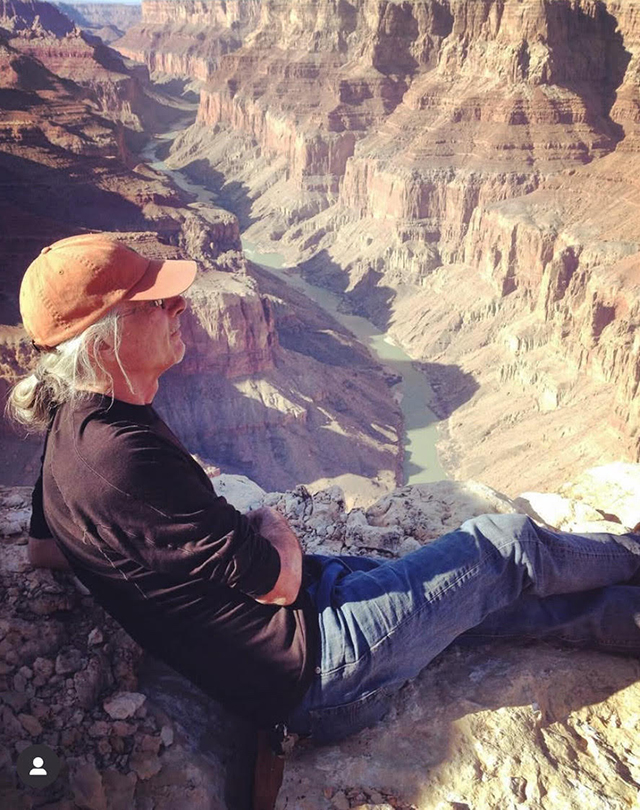 Bruce Aiken sits upon rocks at the Grand Cayon with a view of the Colorado River below. Courtesy Bruce Aiken