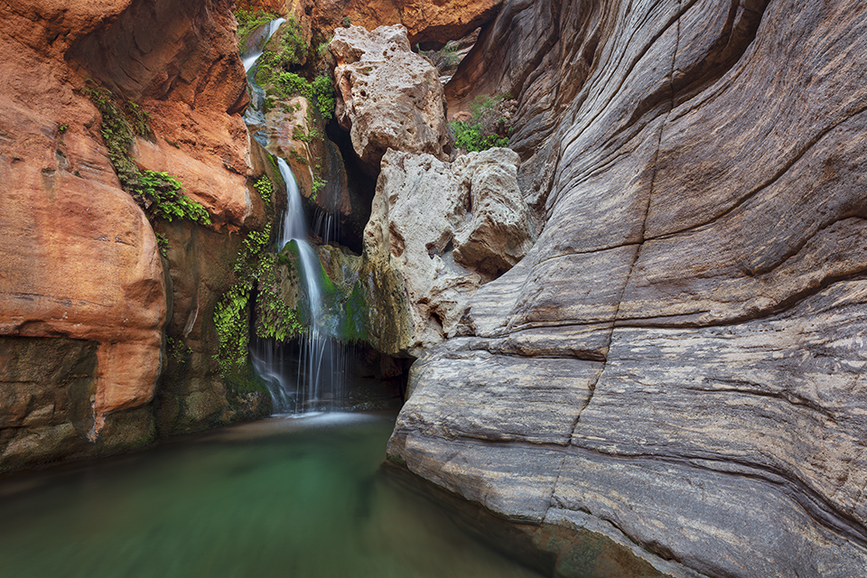 The waterfalls of Elves Chasm, on Royal Arch Creek in the Grand Canyon, nourish greenery clinging to steep canyon walls. Located on the south side of the Colorado River, Elves Chasm is a popular stop for Canyon rafting trips. By Adam Schallau