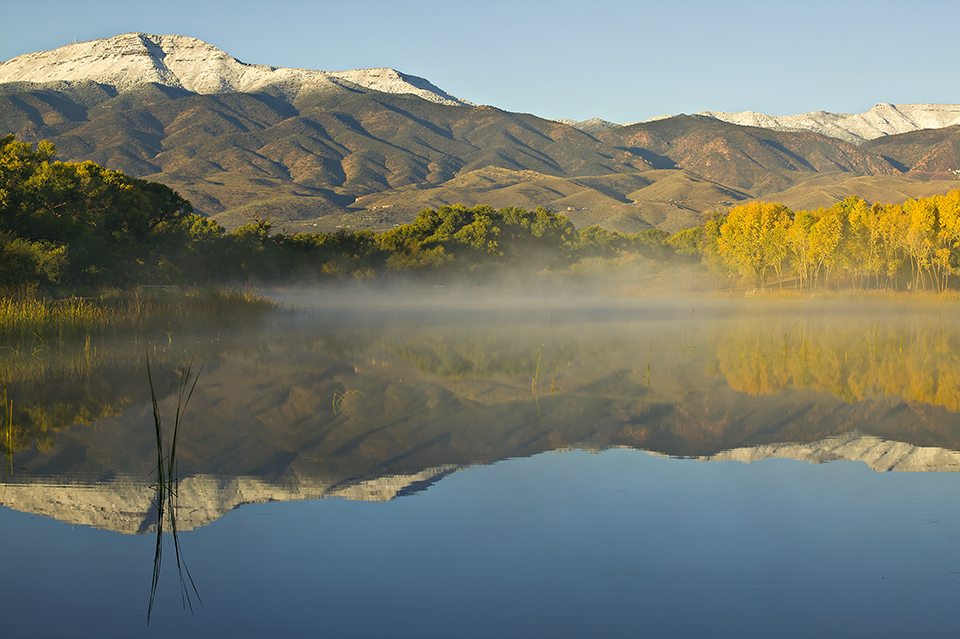 Shrouded by a thin layer of fog, the river’s placid surface mirrors the nearby Black Hills. | Derek von Briesen