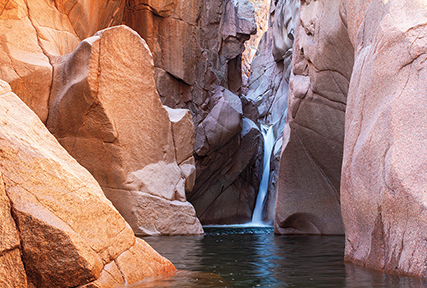 A waterfall drops into a pool surrounded by tall rocks in the Salome Wilderness. By Jonathan Buford
