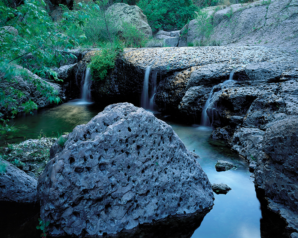 Ancient streams trickle over volcanic boulders in a side canyon, filling pools within Aravaipa Canyon Wilderness. By Randy Prentice