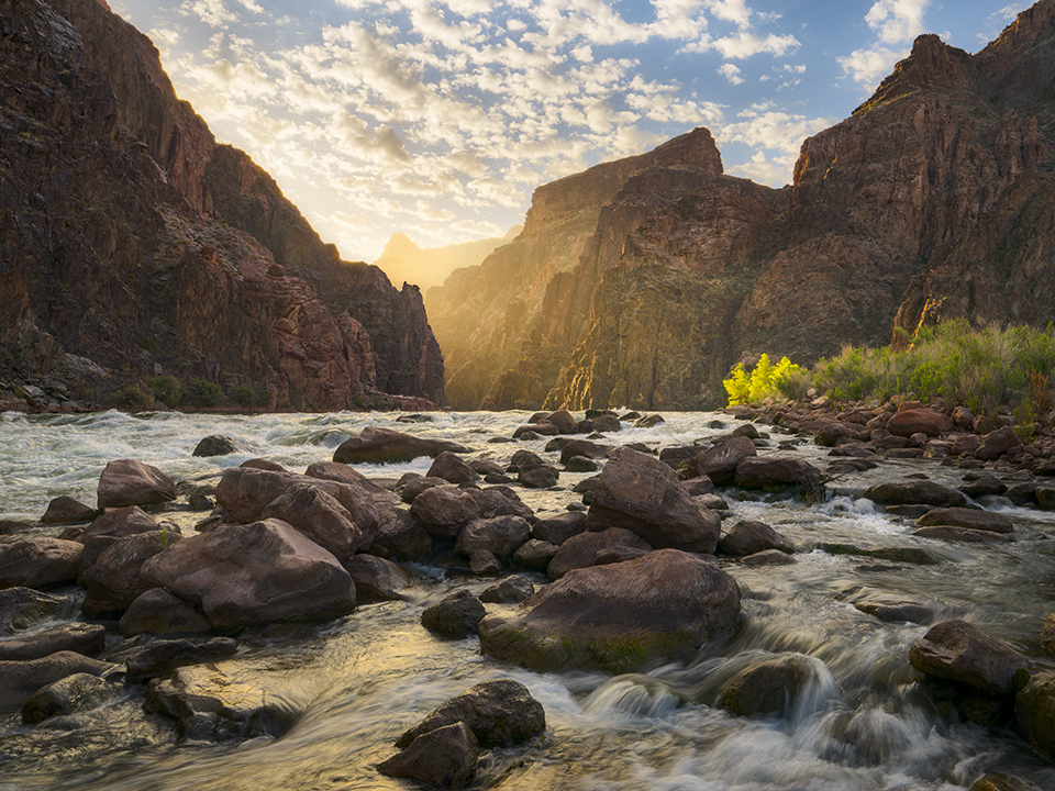 The light of a new day streams through a gap in the dark walls of the Canyon’s Inner Gorge. This view is looking upstream from Granite Rapid, at Mile 94 of the Colorado River’s 277-mile course through the Canyon. By Adam Schallau