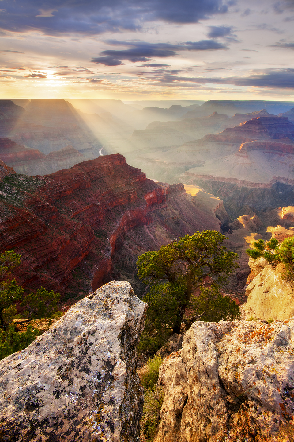 An evening view from Hopi Point, on the South Rim, includes light streaming into the Canyon and a glimpse of the Colorado. Hopi Point is along the Hermit Road, which is open to private vehicles from December through February and to Grand Canyon National Park shuttles at other times of the year. By Adam Schallau