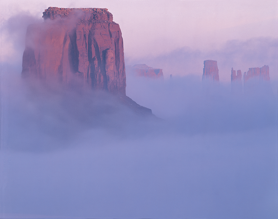 Fog shrouds Merrick Butte (foreground) and other iconic formations in Monument Valley, a Navajo Nation tribal park that attracts some 500,000 visitors annually. Merrick Butte is named for Jack Merrick, who prospected for silver in the area in the late 1800s. | Jack Dykinga