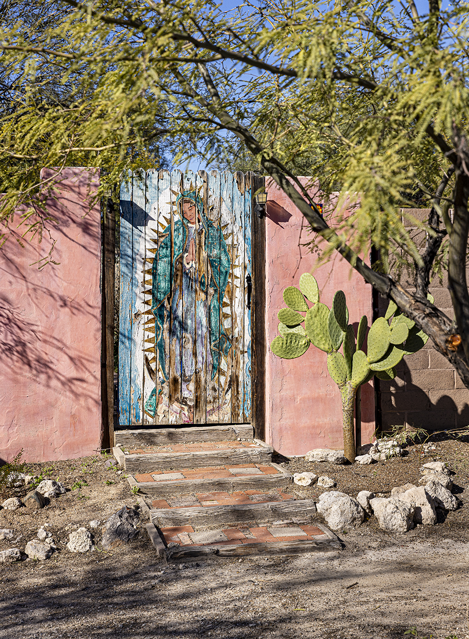 A wooden gate at a house in Tucson's Barrio Santa Rosa displays a weathered painting of Our Lady of Guadalupe. By Steven Meckler