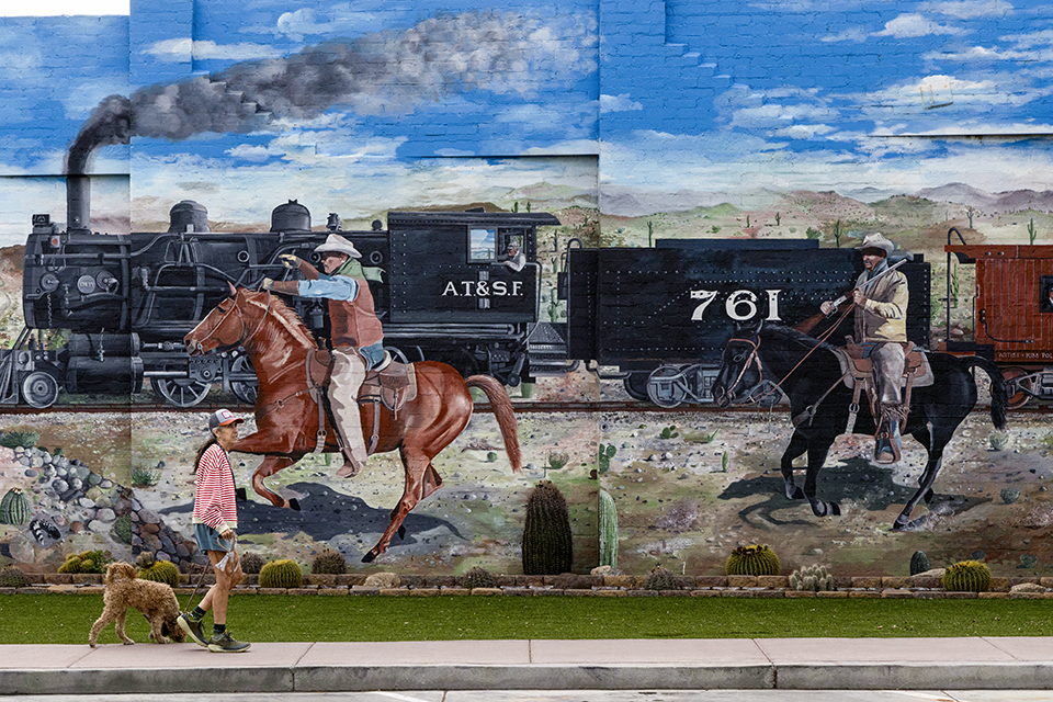 A pedestrian and her dog stroll past a massive mural in downtown Wickenburg. | Mark Lipczynski