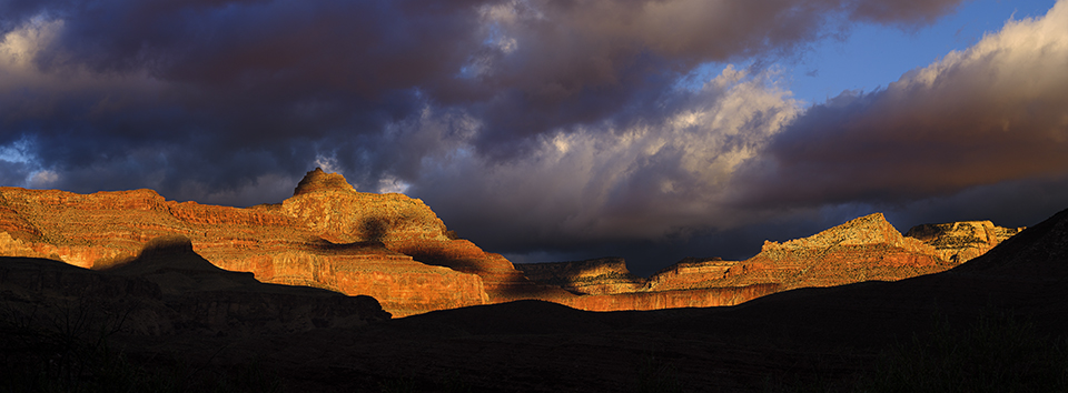 Storm clouds move across Vishnu Temple and the North Rim as the day’s first rays of light paint the cliffs in fiery hues. | ADAM SCHALLAU