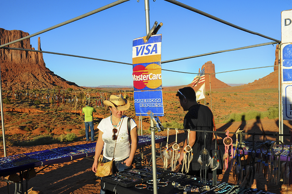 A tourist browses a jewelry stand in Monument Valley advertising that major credit cards are accepted. By Marie Baronnet