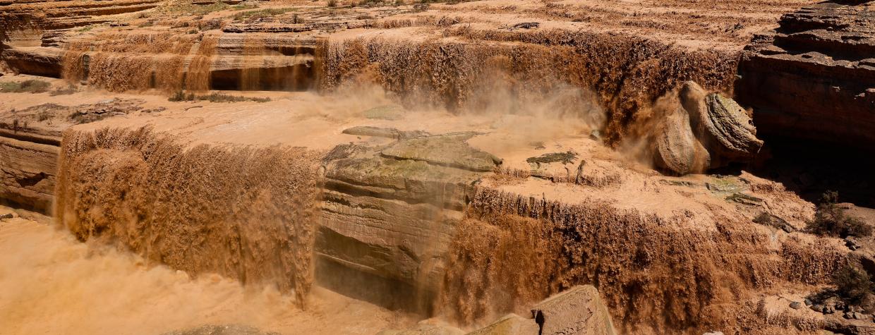 Muddy washes over the natural shelves of Grand Falls.