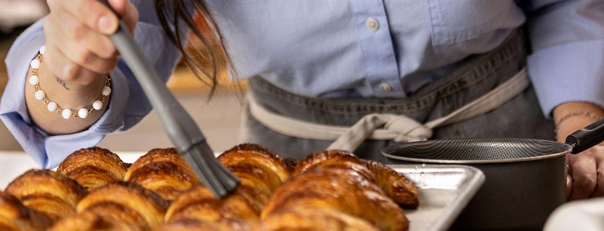 Veronica Regueira brushes a glaze onto croissants at Pampas Bakery. Photo: Paul Markow