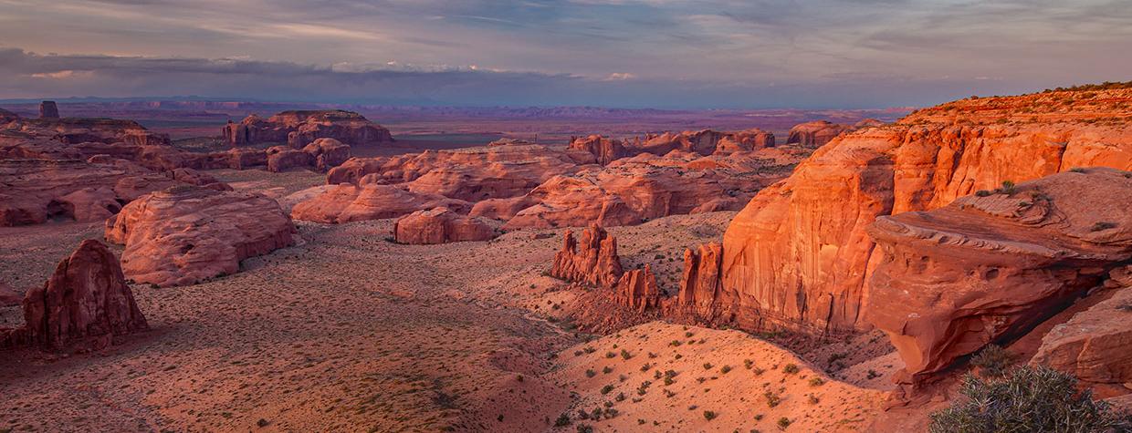 Shadows cloak the sandstone buttes of Monument Valley in a sunset view from Hunts Mesa. By Larry Lindahl