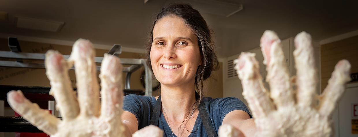Rachelle Wingfield shows off doughy hands for the camera in her bakery kitchen. By Dawn Kish