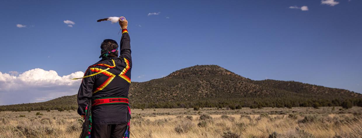 Stuart Chavez, a member of the Havasupai Tribe, raises an eagle feather toward Red Butte, one of the tribe’s sacred sites. By Eirini Pajak