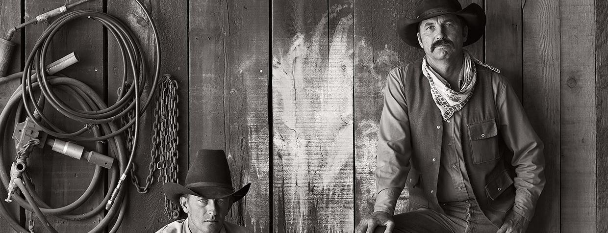 Black and white photo of cowboys Buster Scarbrough and Bob Pulley pose for a photo at the A Bar V Ranch in Skull Valley in 1981. This shot was one of several Jay Dusard photos published in the August 1982 issue of Arizona Highways. 