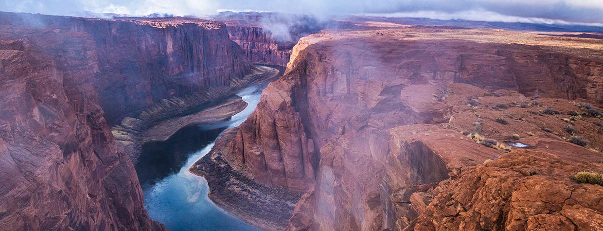 Fog and mist lift from Glen Canyon, revealing the sky reflected in the water below. By Gary Ladd