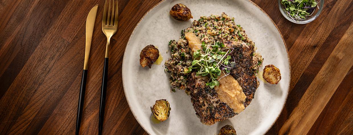 Herb crusted pork chops with sausage, apple, pecan and quinoa dressing, apple bourbon sauce and browned butter Brussels sprouts. By Rob Ballard