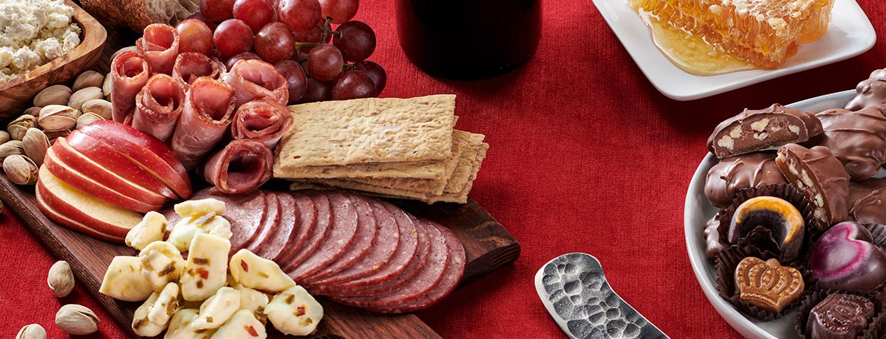 Assorted food gifts, including nuts, chocolates, olives, cheese and salami.