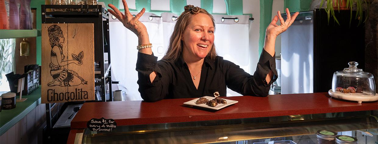 Sarah Ann Lesslie behind a counter displaying fine chocolates at Chocolita.