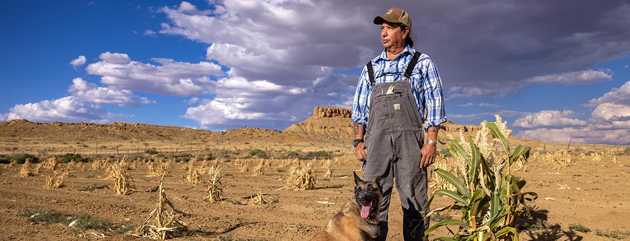 Michael Kotutwa Johnson, a Hopi farmer, and his dog gaze out over farmland in Northeastern Arizona. By John Burcham