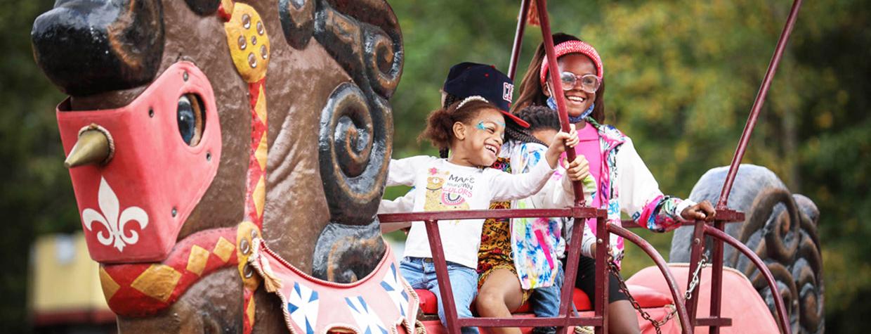 Four children with big smiles ride the giant rocking horse at the Arizona Renaissance Fair.