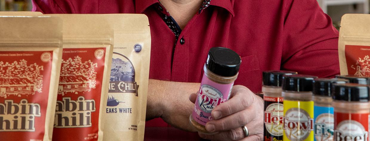 Jeremy Cox in a store setting with a selection of his chili mixes and rubs. By Paul Markow