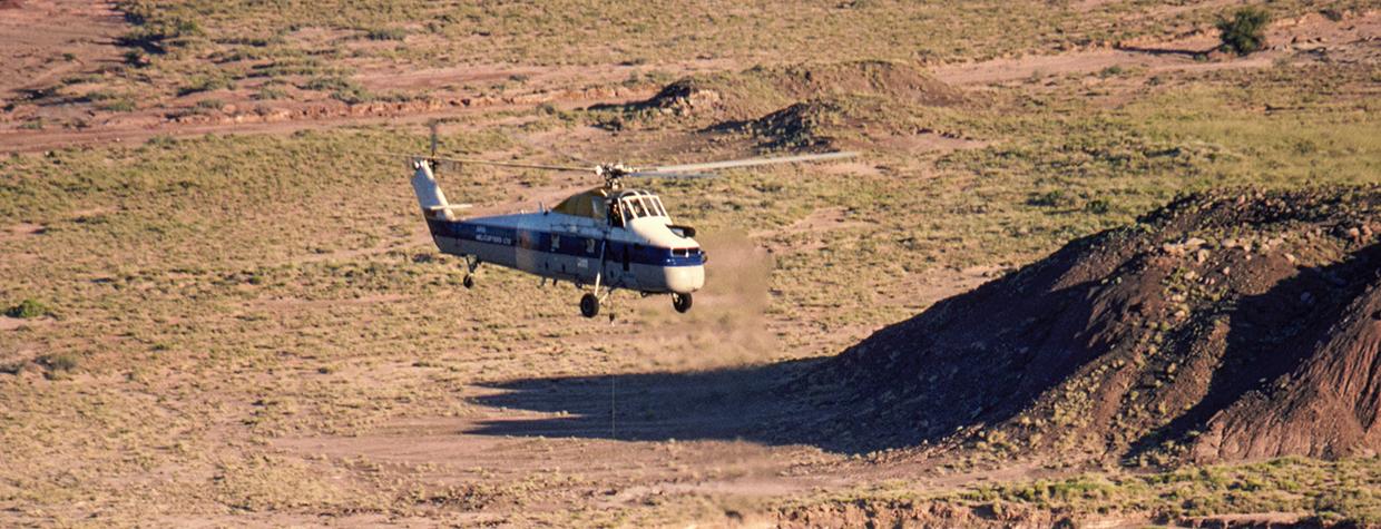 A Sikorsky helicopter lifts the remains of Chindesaurus bryansmalli, a dinosaur popularly known as “Gertie,” from the layered landscape  of Petrified Forest National Park on June 6, 1985. The fossilized dinosaur was discovered near what now is called Hózhó Point. | Jeff Kida