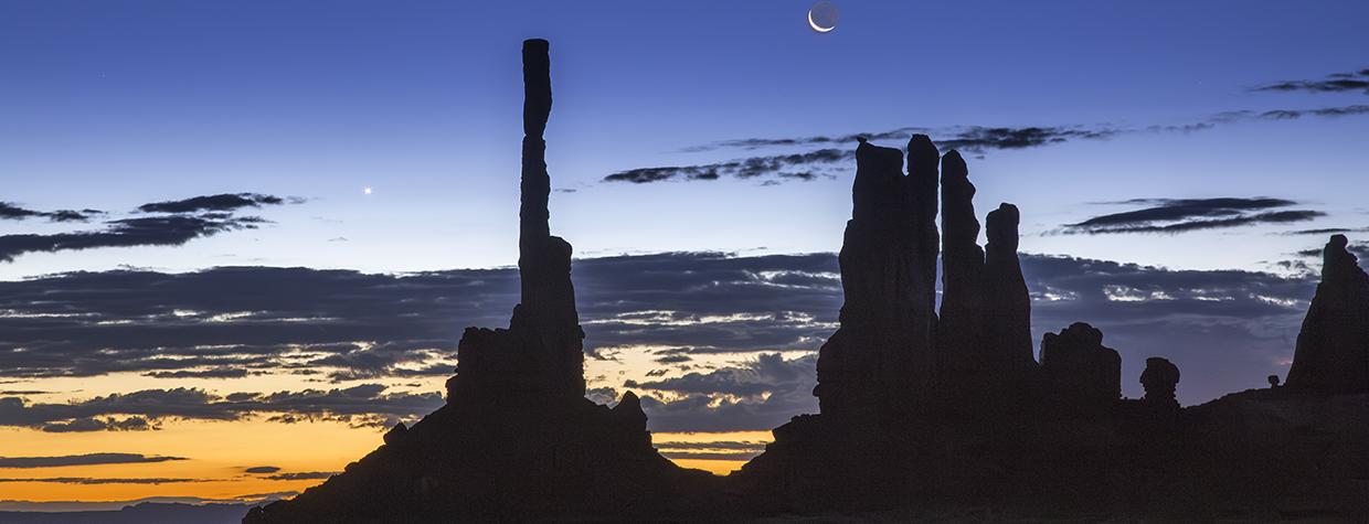Dawn and night briefly share the sky over Ye Bi Chei at Monument Valley, in Northeastern Arizona. The Navajo people, on whose land this photograph was made, have strong spiritual beliefs tied to the moon. By Suzanne Mathia