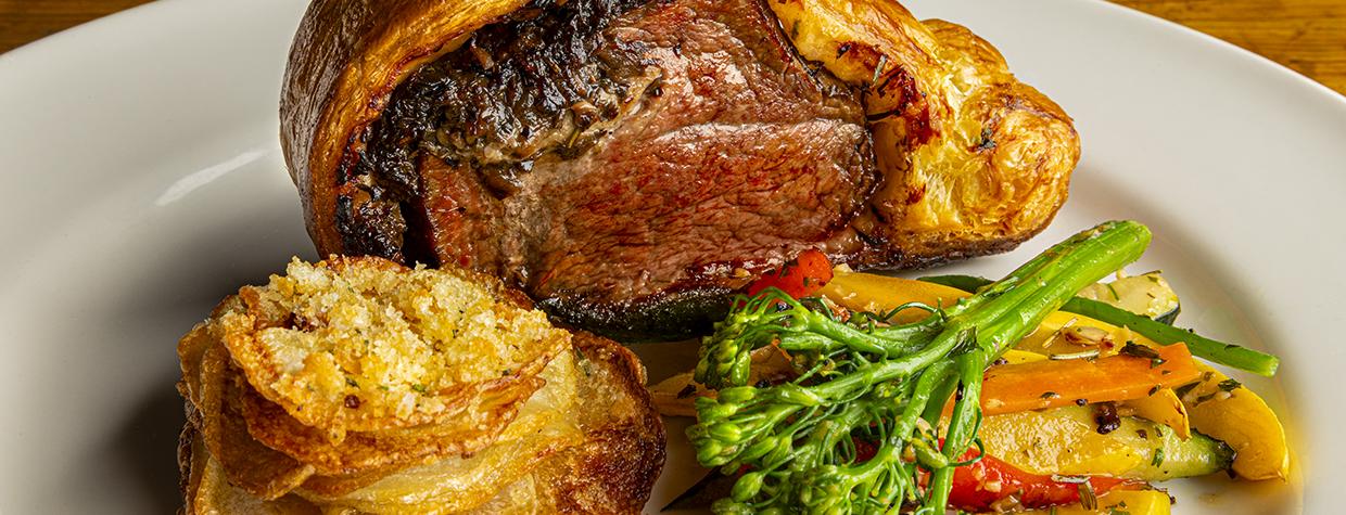 Beef Wellington with potato slices and vegetables fill a plate at Le Rendez-vous. By Steven Meckler