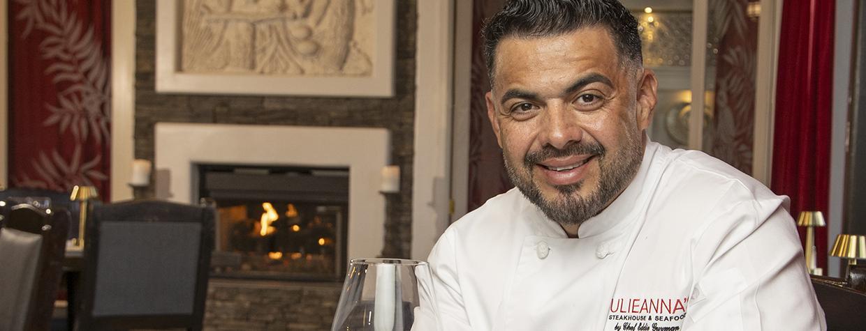 Eddie Guzman poses at Julianna's with a signature steak dish and a glass of red wine. By Paul Markow