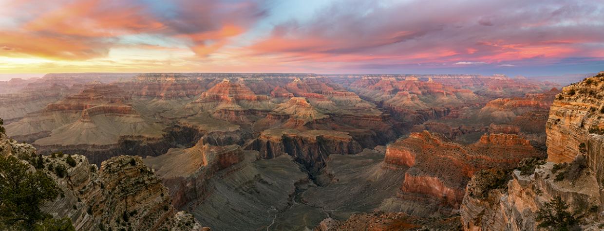 The setting sun colors the sky over the layered buttes of the Grand Canyon, as seen from the South Rim. Frequent visitors recommend arriving at the rim an hour before sundown to fully experience a sunset at the Canyon. By Adam Schallau