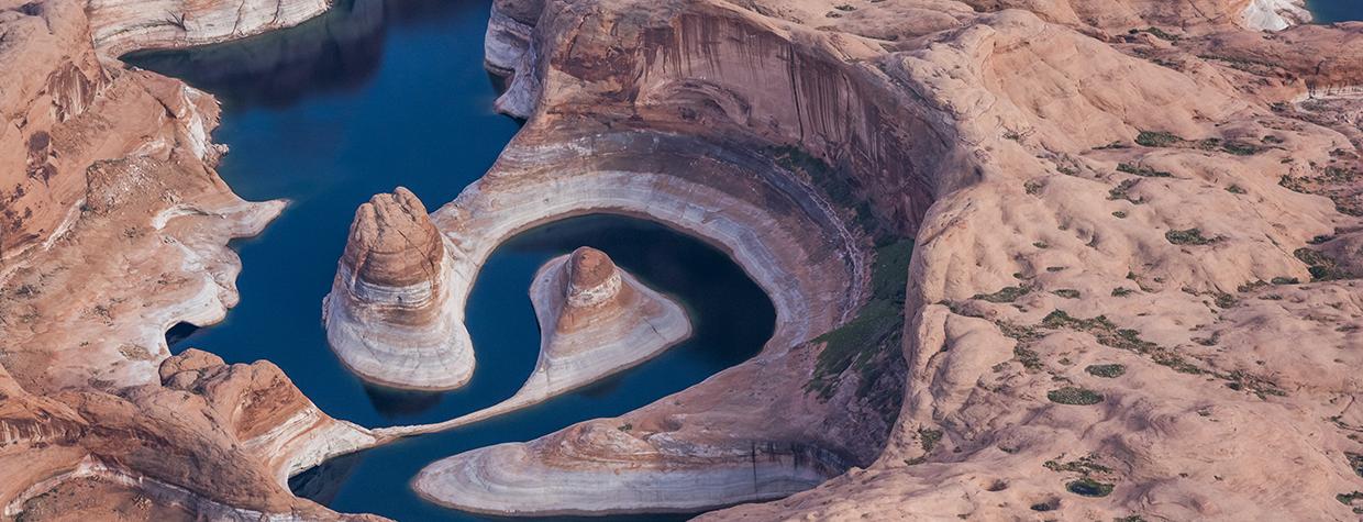 An aerial photo of Lake Powell’s Reflection Canyon displays the reservoir’s current and former water levels, along with the canyon’s looping course. By Gary Ladd
