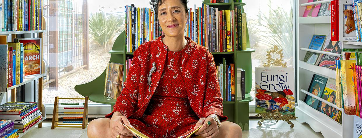 Cheron Taylor sits on a play rug in front of a bookshelf shaped like a dinosaur in the kid's section of Desierto Books in Tucson. | Steven Meckler