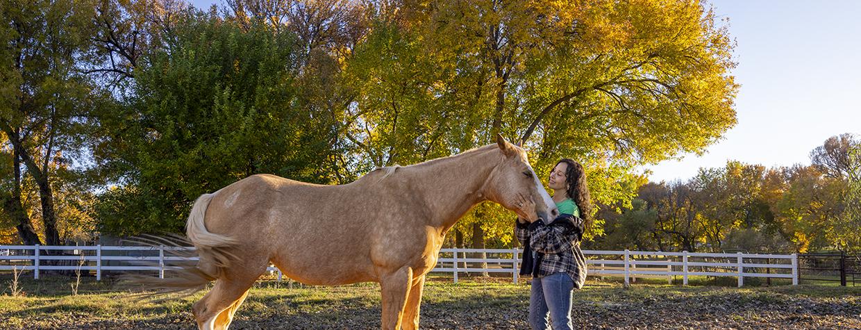 Joanne Cacciatore lovingly cradles the contented face of Chemakoh, a tan rescue horse, at Selah Carefarm, near Sedona. By John Burcham