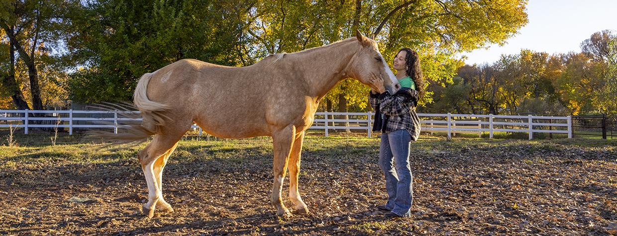 Joanne Cacciatore lovingly cradles the contented face of Chemakoh, a tan rescue horse, at Selah Carefarm, near Sedona. By John Burcham