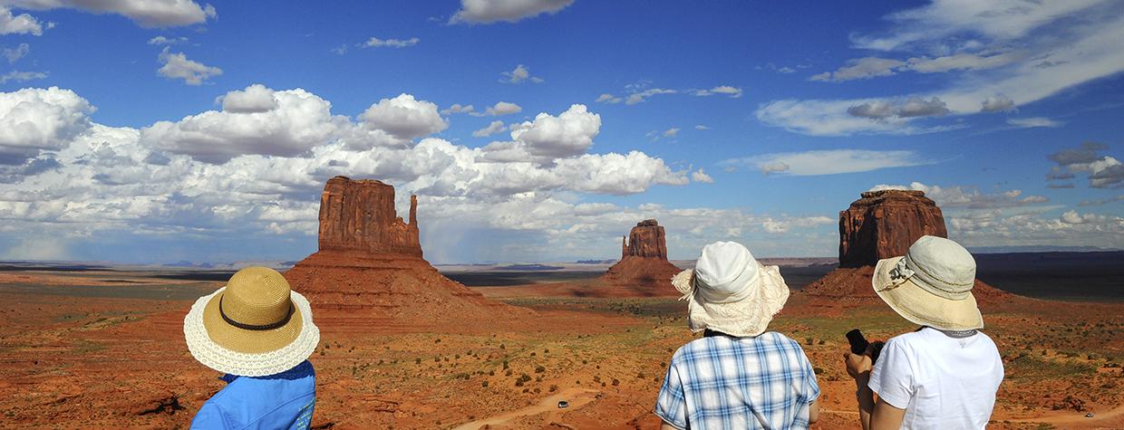 Three Japanese tourists take in a view of The Mittens in Monument Valley. By Marie Baronnet