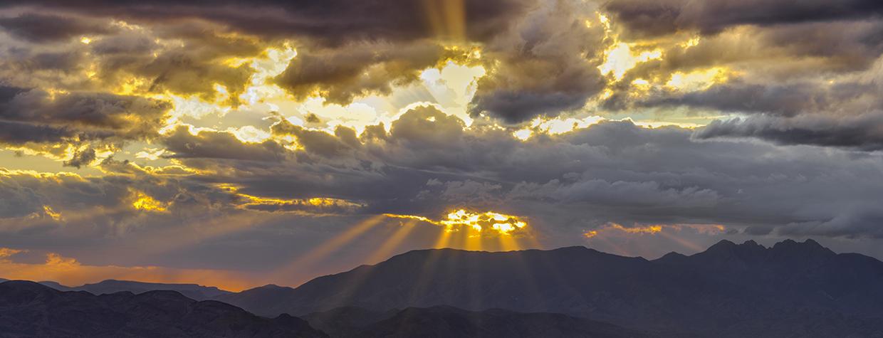 Rays of sunlight burst through dark and gloomy storm clouds at Parker Canyon. | Claire Curran