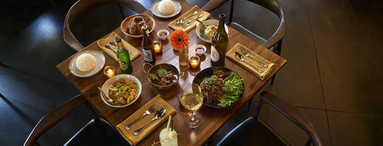 A table for four at Lom Wong is set with bar drinks and entreés including salad, pasta and meat dishes. | David Zickl