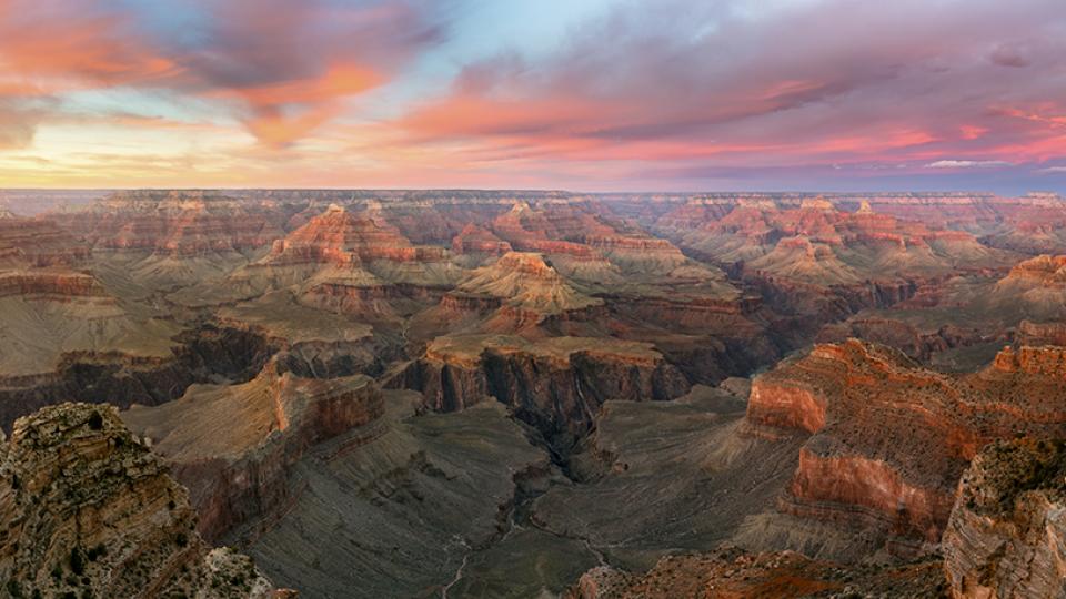 The setting sun colors the sky over the layered buttes of the Grand Canyon, as seen from the South Rim. Frequent visitors recommend arriving at the rim an hour before sundown to fully experience a sunset at the Canyon. By Adam Schallau