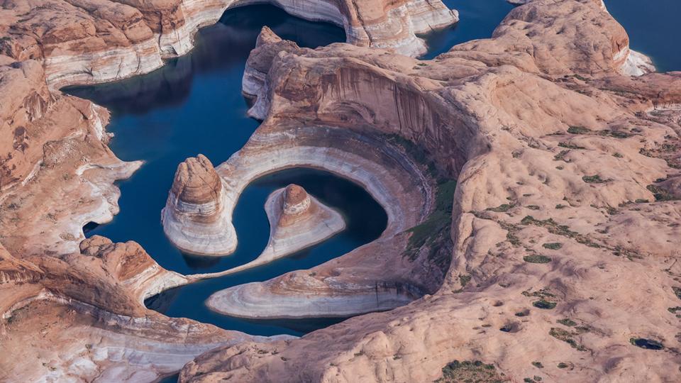 An aerial photo of Lake Powell’s Reflection Canyon displays the reservoir’s current and former water levels, along with the canyon’s looping course. By Gary Ladd