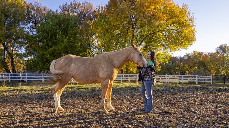 Joanne Cacciatore lovingly cradles the contented face of Chemakoh, a tan rescue horse, at Selah Carefarm, near Sedona. By John Burcham