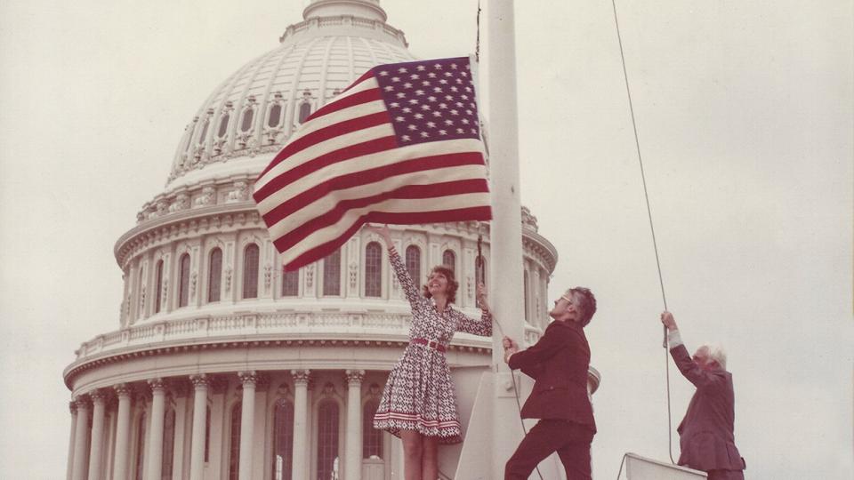 On June 14, 1976, Carolyn Hartmann (left) and Associate Editor Wes Holden (center) flew an American “flag rug” over the U.S. Capitol.